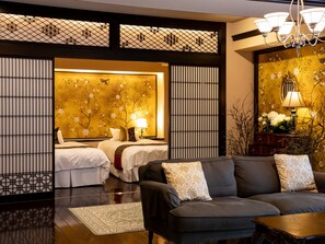 Habitación de hotel con diseño tradicional, que incluye un sofá, una cama con ropa de cama blanca y una pared decorativa con motivos florales.