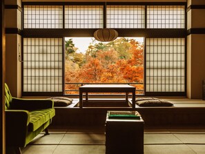 Una habitación japonesa tradicional con suelo de tatami, una mesa baja y un sofá.