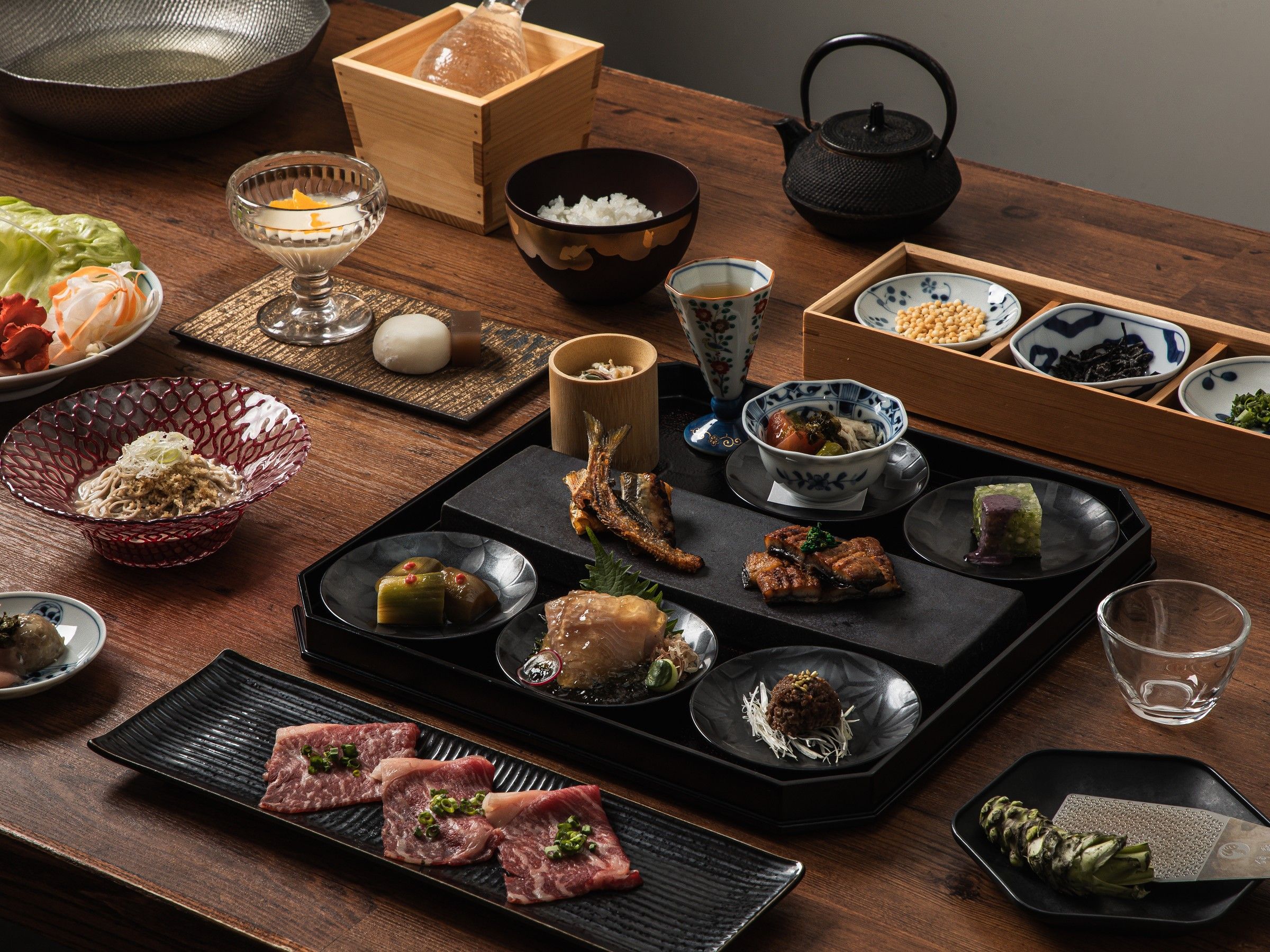 A traditional Japanese meal setup with various dishes and utensils on a wooden table.