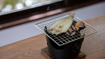 Un barbecue portable avec une brochette de poisson et une brochette de viande sur une table en bois.