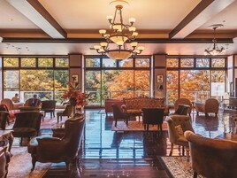 Un hallo amplio con un candelabro, ventanas grandes y diversas opciones de asientos.