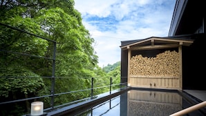 Un espace bien-être comprenant un sauna en bois, une piscine à débordement et une vue sur une végétation luxuriante.