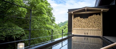 Un área de spa con sauna de madera, piscina de cristal y vistas a exuberante vegetación.