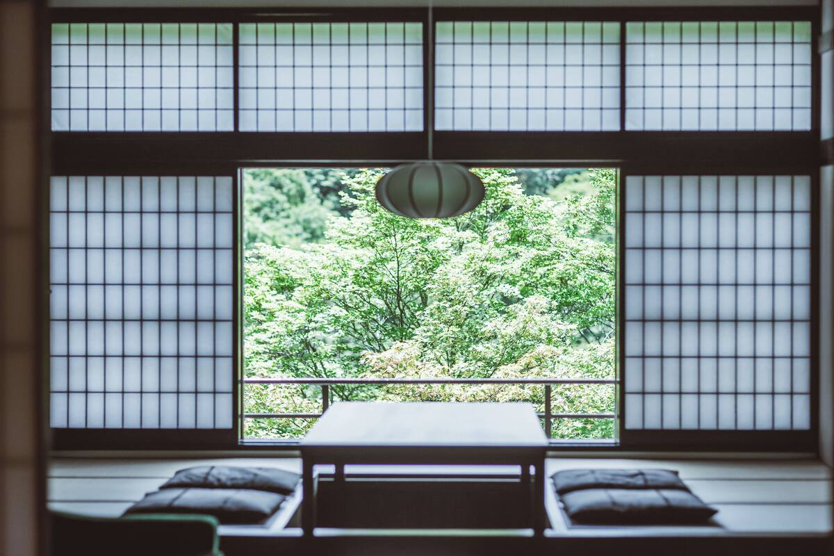 Ein traditioneller japanischer Raum mit Tatami-Bodenbelag, einem niedrigen Tisch und Kissen.