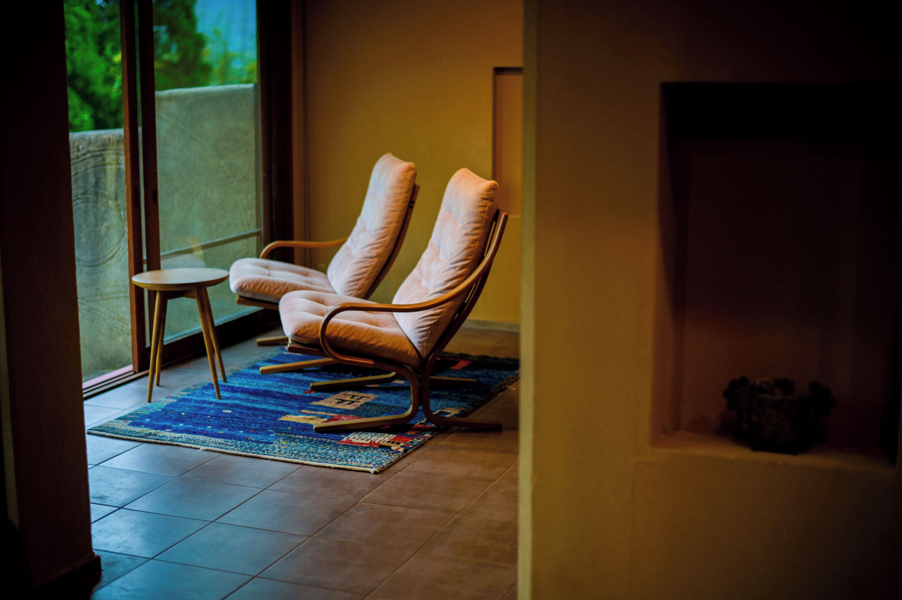 Una habitación con dos sillones de cuero, una mesita redonda y un tapete colorido.