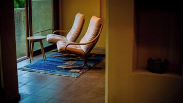 Una habitación con dos sillones de cuero, una mesita redonda y un tapete colorido.