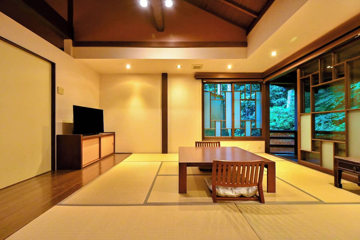 Une pièce de style japonais traditionnel, avec un sol recouvert de tatamis, une basse table en bois et un téléviseur posé sur un meuble.