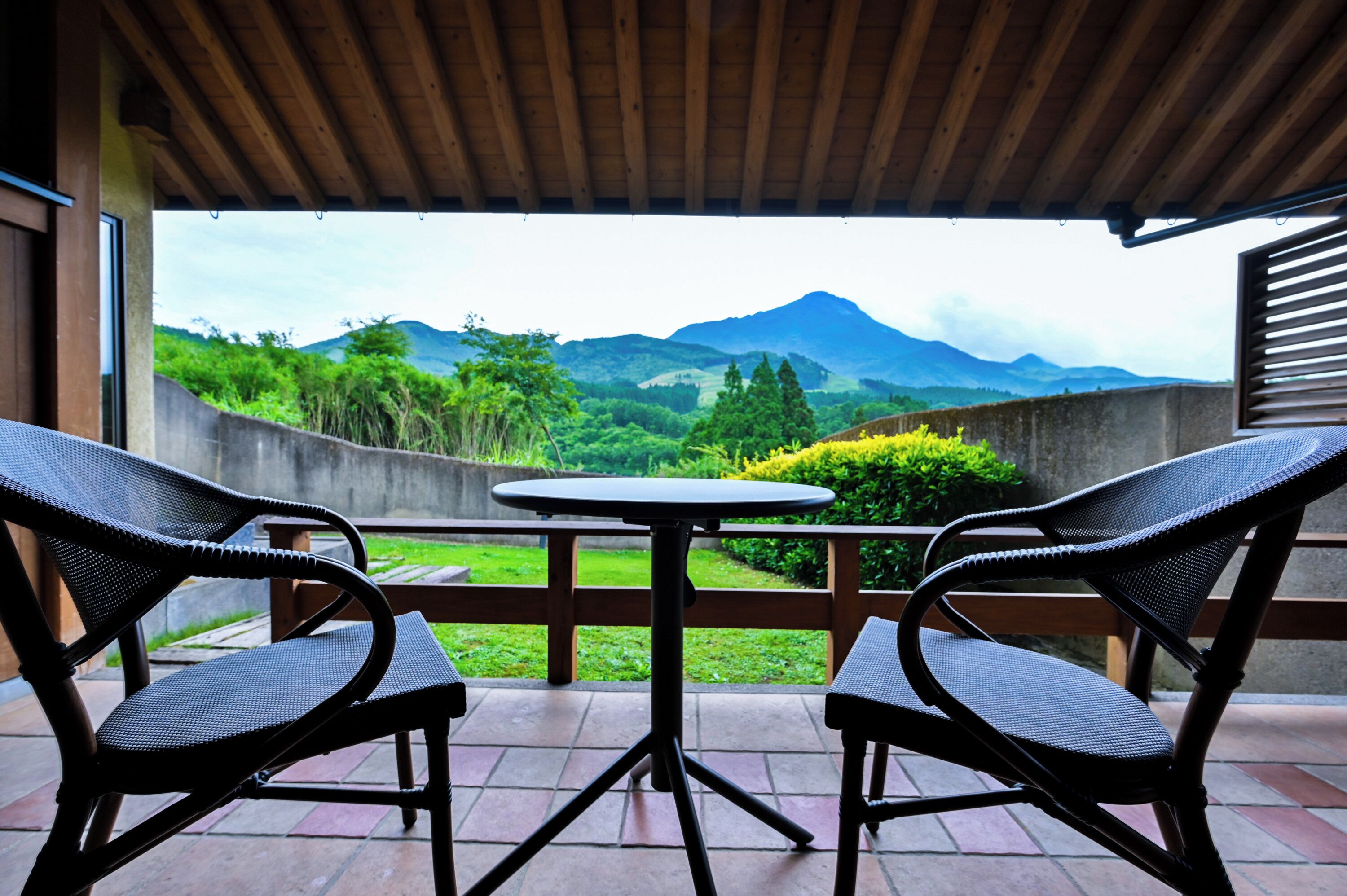 Un espace extérieur abrité, aménagé avec deux chaises et une table, offrant une vue sur un paysage montagneux.