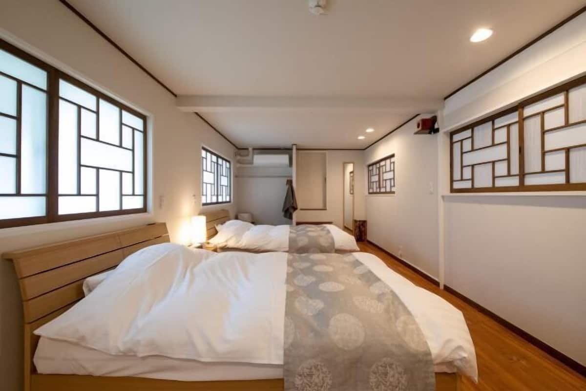 Une chambre à coucher avec un grand lit, une table de chevet, une fenêtre donnant sur un beau paysage et un mur agrémenté d’un panneau décoratif.