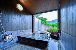 Un espace de bien-être avec un jacuzzi, des murs en bois et une vue sur la verdure.