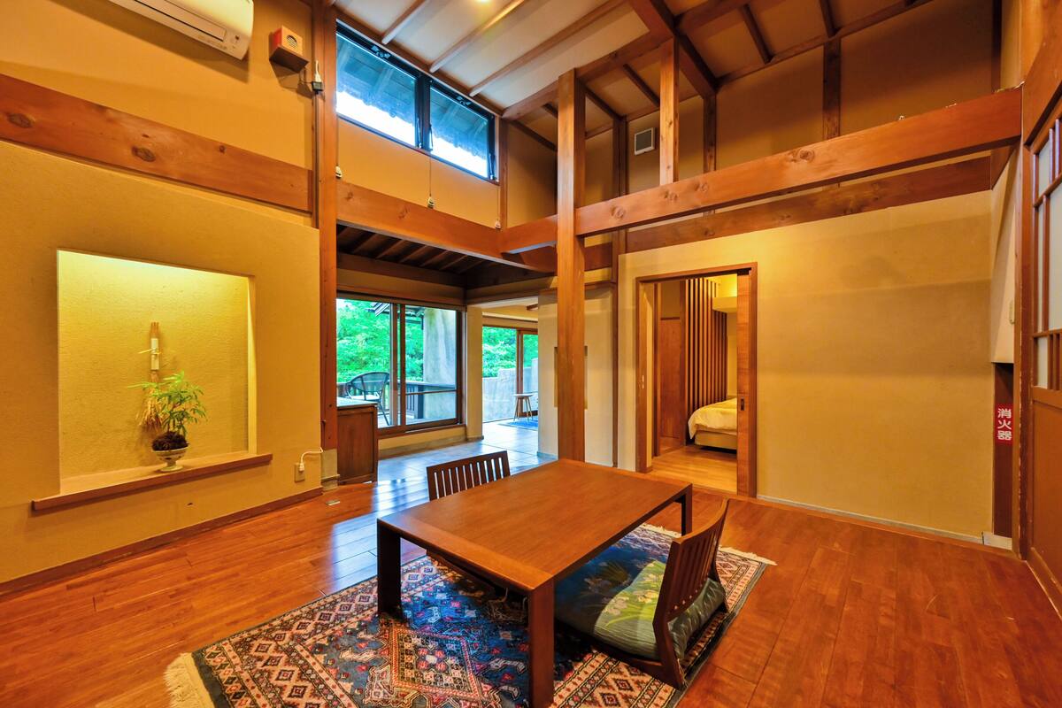 Une pièce de style japonais traditionnel, avec un plancher en bois, des tatamis servant de sièges, une petite table basse et des portes coulissantes.