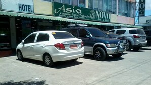 A parking lot with several cars, a hotel sign, and a store named 'Asia' and 'NOVO'. - Asia Novo Boutique Hotel - Roxas (Roxas City)
