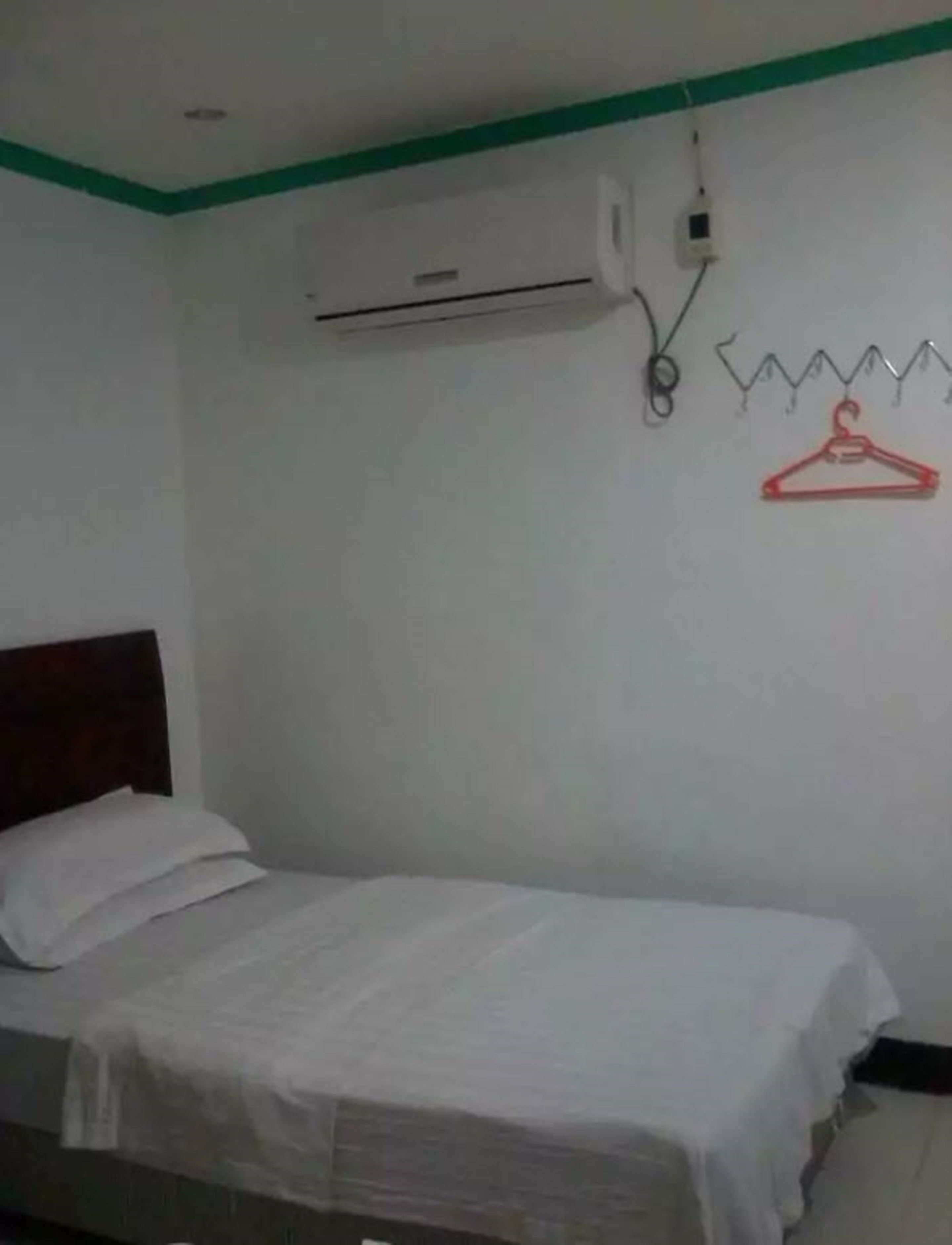 A single bed with white bedding in a room with a green-painted ceiling and white walls.