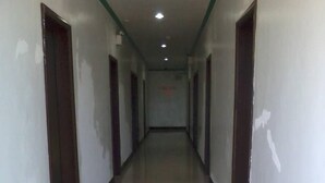 A long, narrow hallway with white tiled floors and dark wooden doors on both sides. - Asia Novo Boutique Hotel - Roxas (Roxas City)