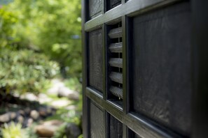 A close-up of a wooden door with a window, set against a blurred natural background. - Sui Suwako (Suwa)