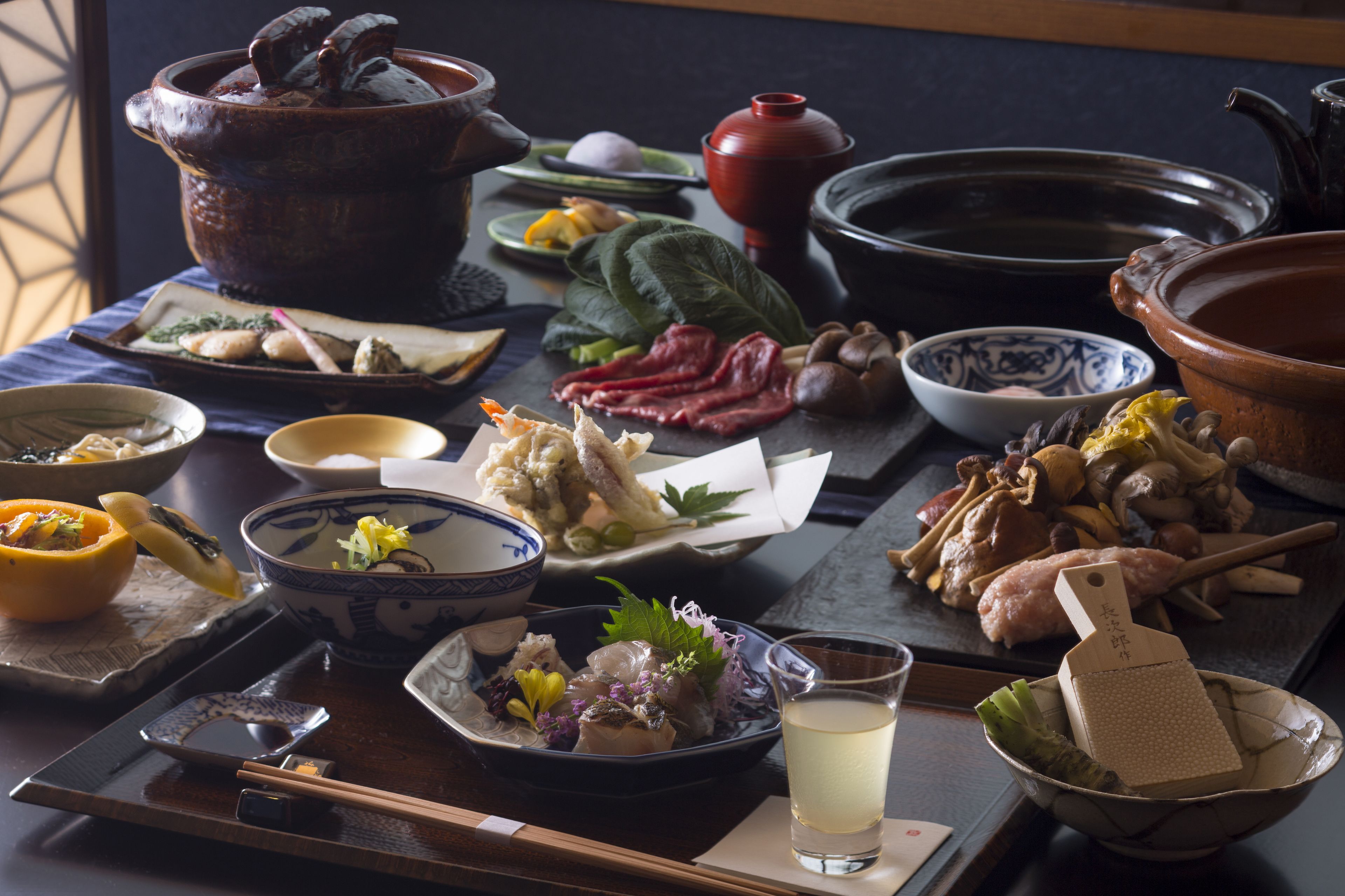 A traditional Japanese meal setup with various dishes, including a pot, bowls, and chopsticks.