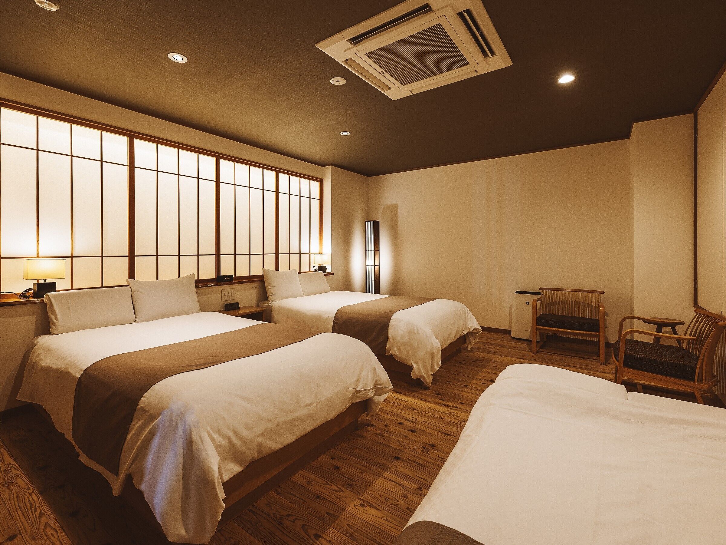 Habitación de hotel con dos camas, zona de estar y un ventanal grande.