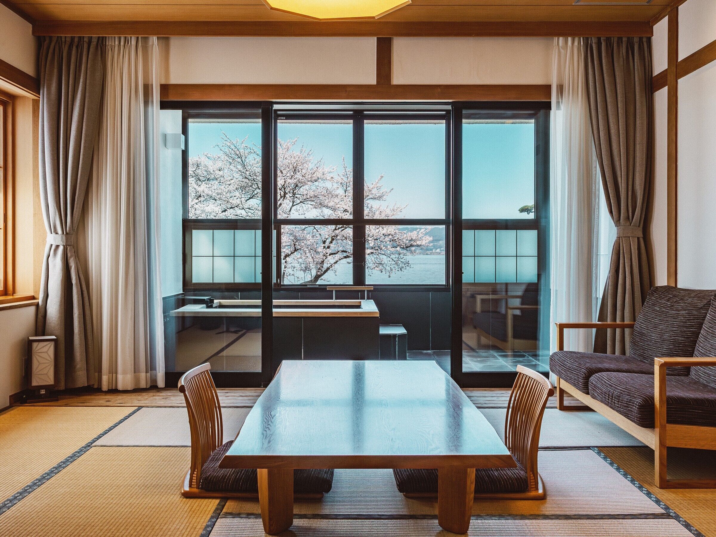 Perinteinen japanilaistyylinen huone, jossa on tatamimatto, matala pöytä ja sohva.