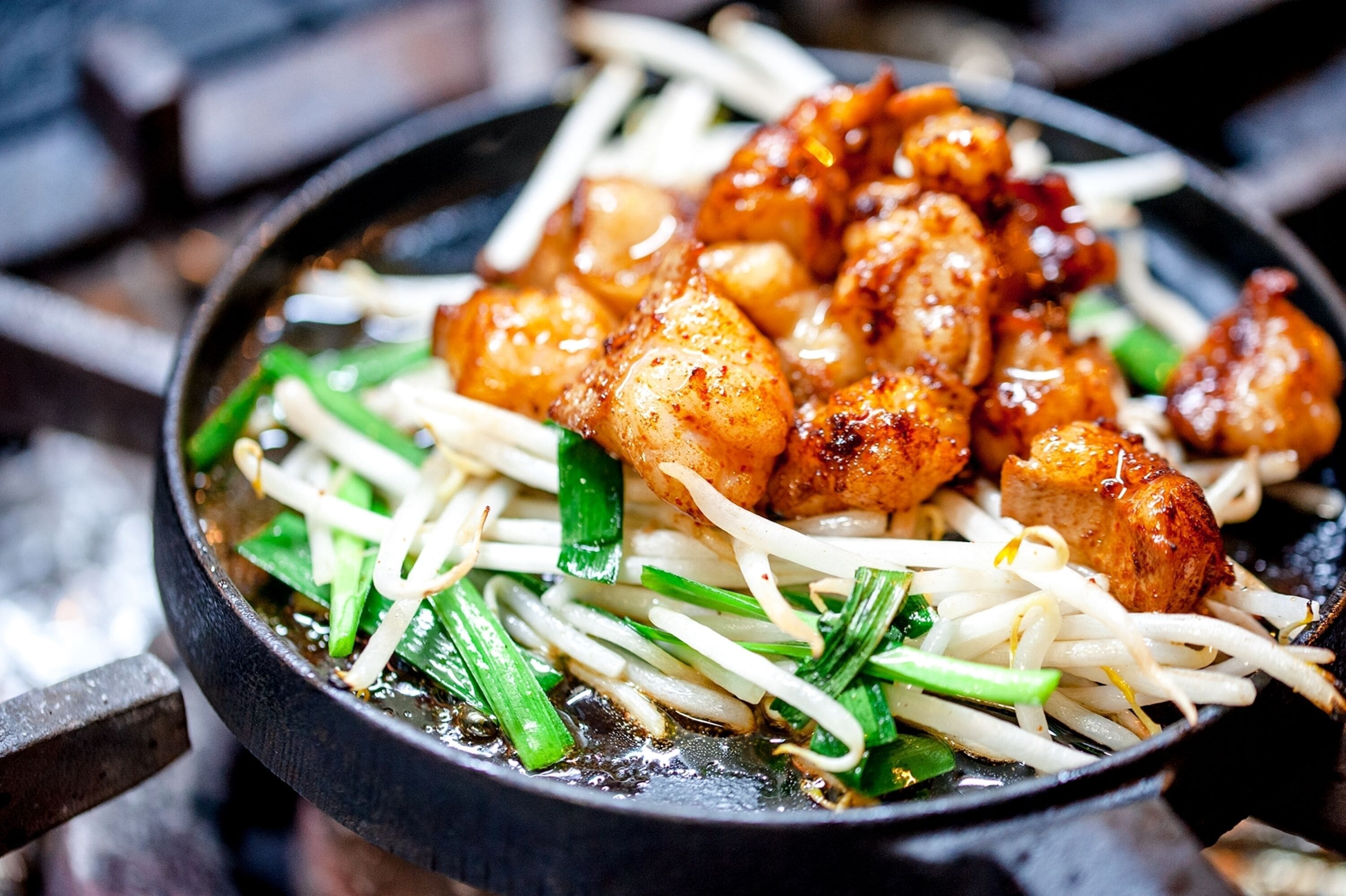 A bowl of stir-fried noodles with vegetables and meat.