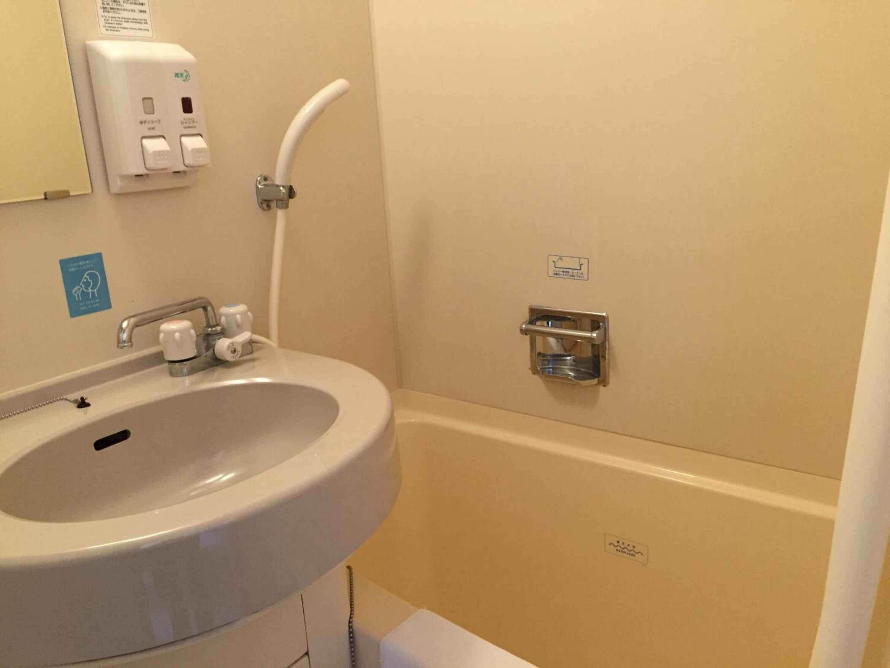 A bathroom with a sink, a hand dryer, a paper towel dispenser, and a toilet.