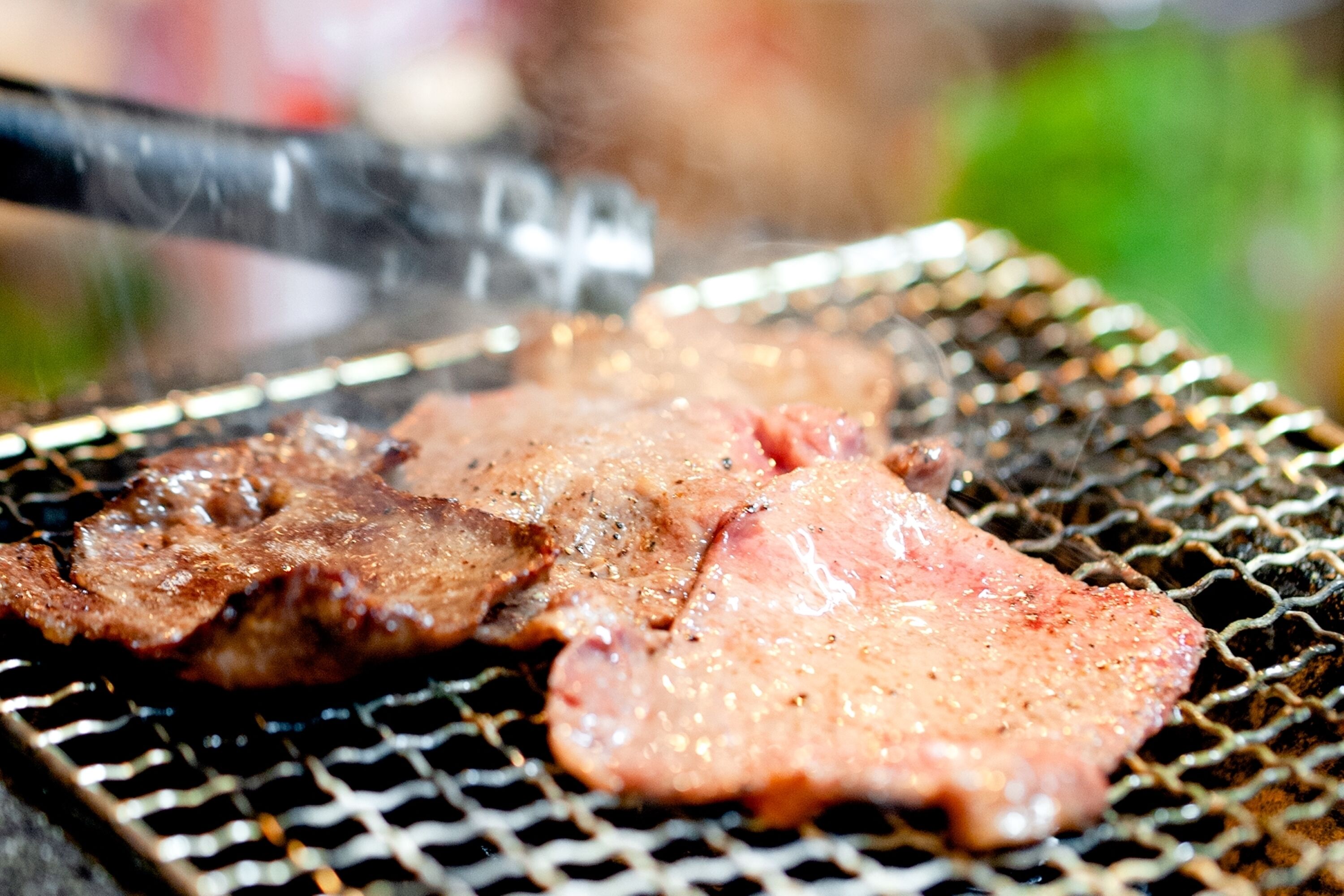 Primer plano de carne asándose en una parrilla.