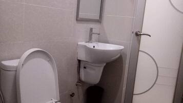 A small, compact bathroom with a toilet, sink, and mirror.