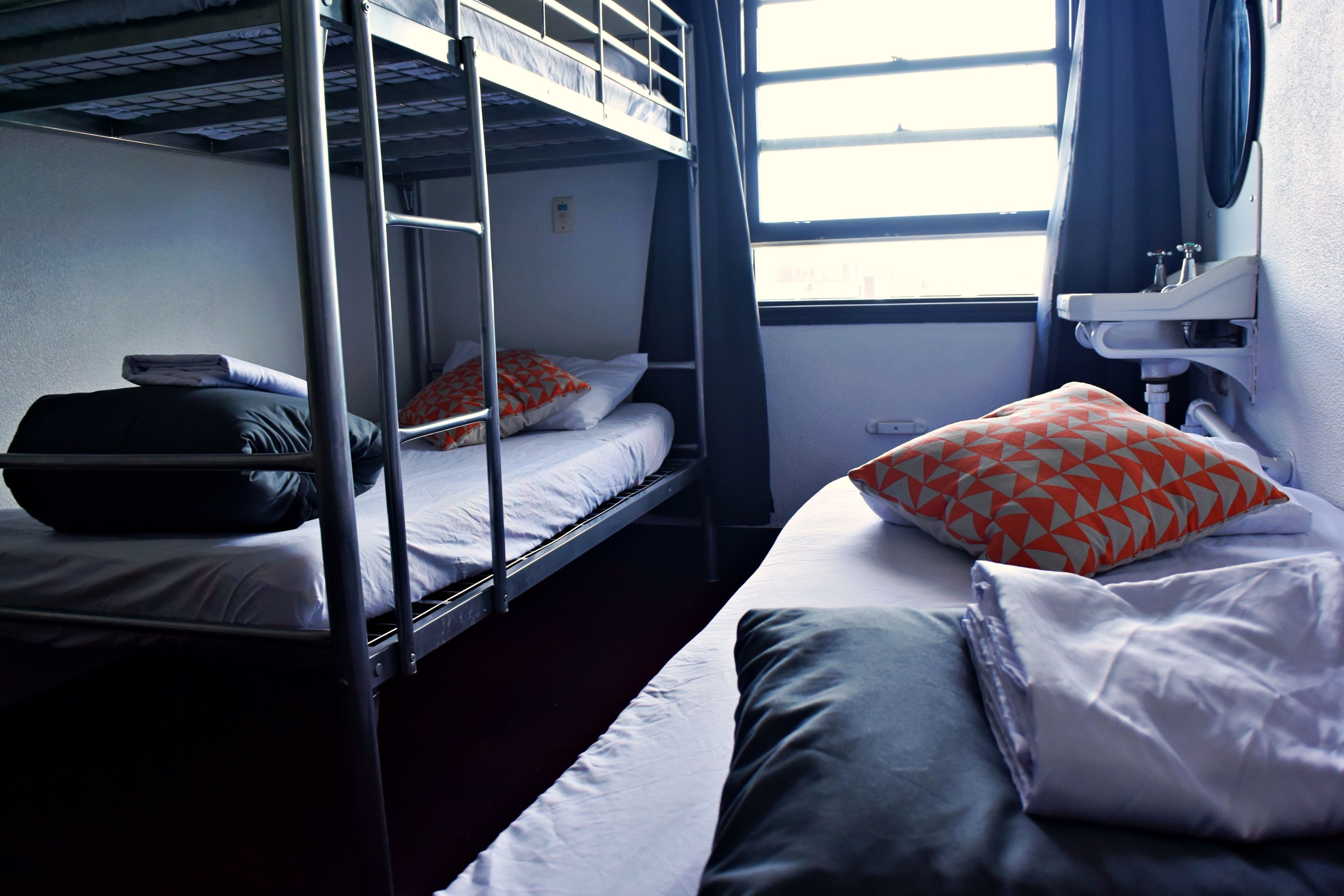 A bunk bed room with a window, a sink, and a mirror.