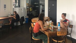 A dining area with wooden tables and chairs, a kitchen in the background, and a door marked "Private." - BoBs Hostel (Taupo)