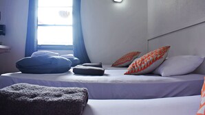 A bedroom with a bed, pillows, a window, and a ceiling light. - BoBs Hostel (Taupo)