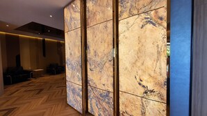 Un interior moderno con piso de madera en espiga, un gran separador de mármol y una zona de estar con sofás y una mesita de centro.