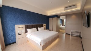 Una habitación de hotel moderna con una cama grande, mesitas de noche, un armario y un espejo.