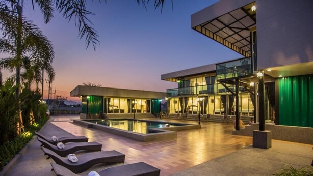 A modern hotel with a swimming pool, lounge chairs, and a glass staircase. - Royal Graces Pool Villas (Cha-am)