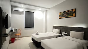 A hotel room with two beds, a TV, a desk, a chair, a window, and a painting on the wall. - Urban Style Hotel Lampung, Azana Hotels Collection (Gedongtataan)
