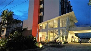 Um edifício moderno com fachada de vidro, escadaria e área de entrada bem iluminada.