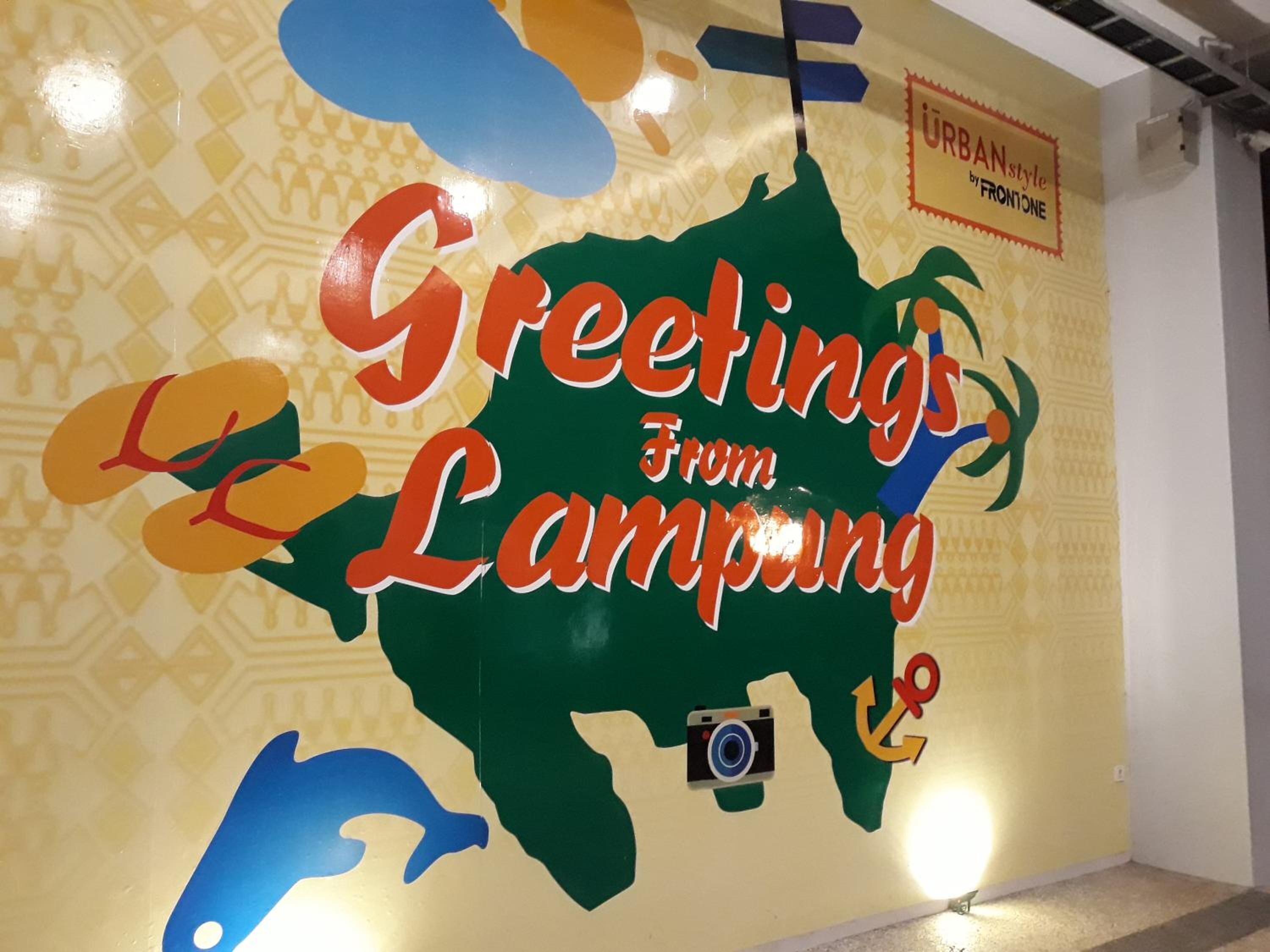 Un muro con un mapa de Lampung y el texto 'Greetings From Lampung', junto con un icono de cámara y un ancla.
