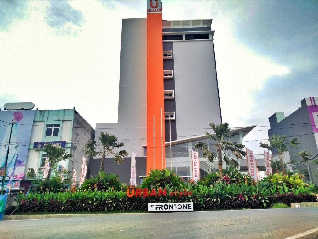 A hotel with a prominent orange and grey facade, surrounded by lush greenery and palm trees.