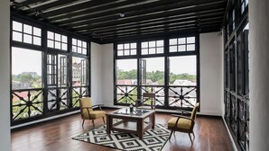 Una habitación amplia con ventanas grandes, piso de madera y una mesa central con sillas.