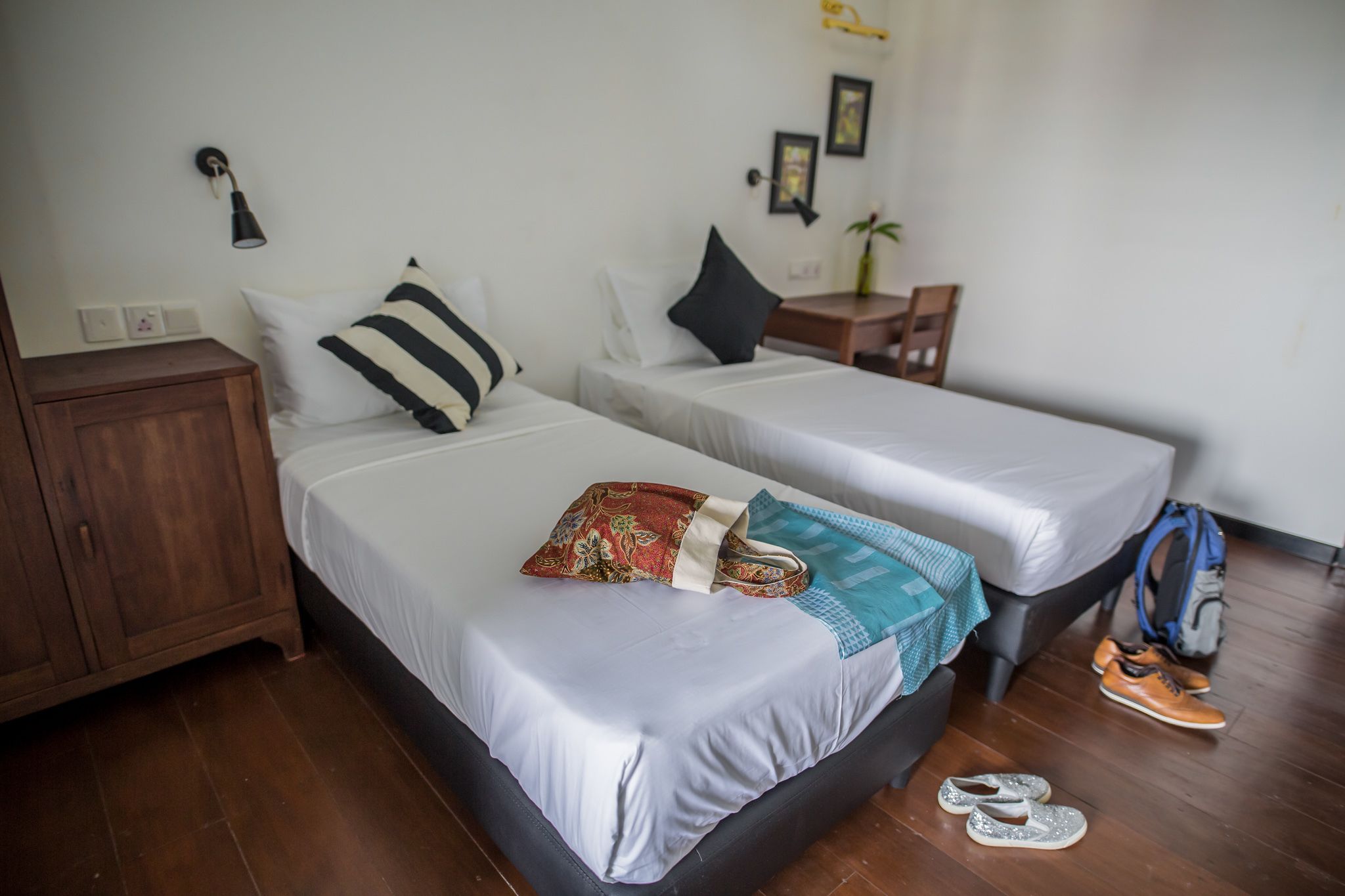 A hotel room with two beds, a wooden nightstand, a desk, and a chair.
