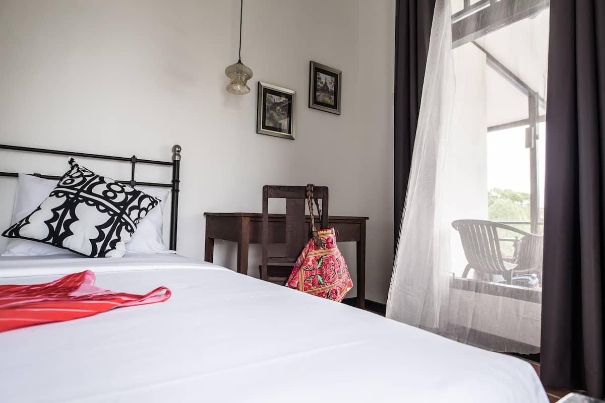 Une chambre d’hôtel avec un lit, un bureau et une chaise. Deux tableaux encadrés sont accrochés au mur.
