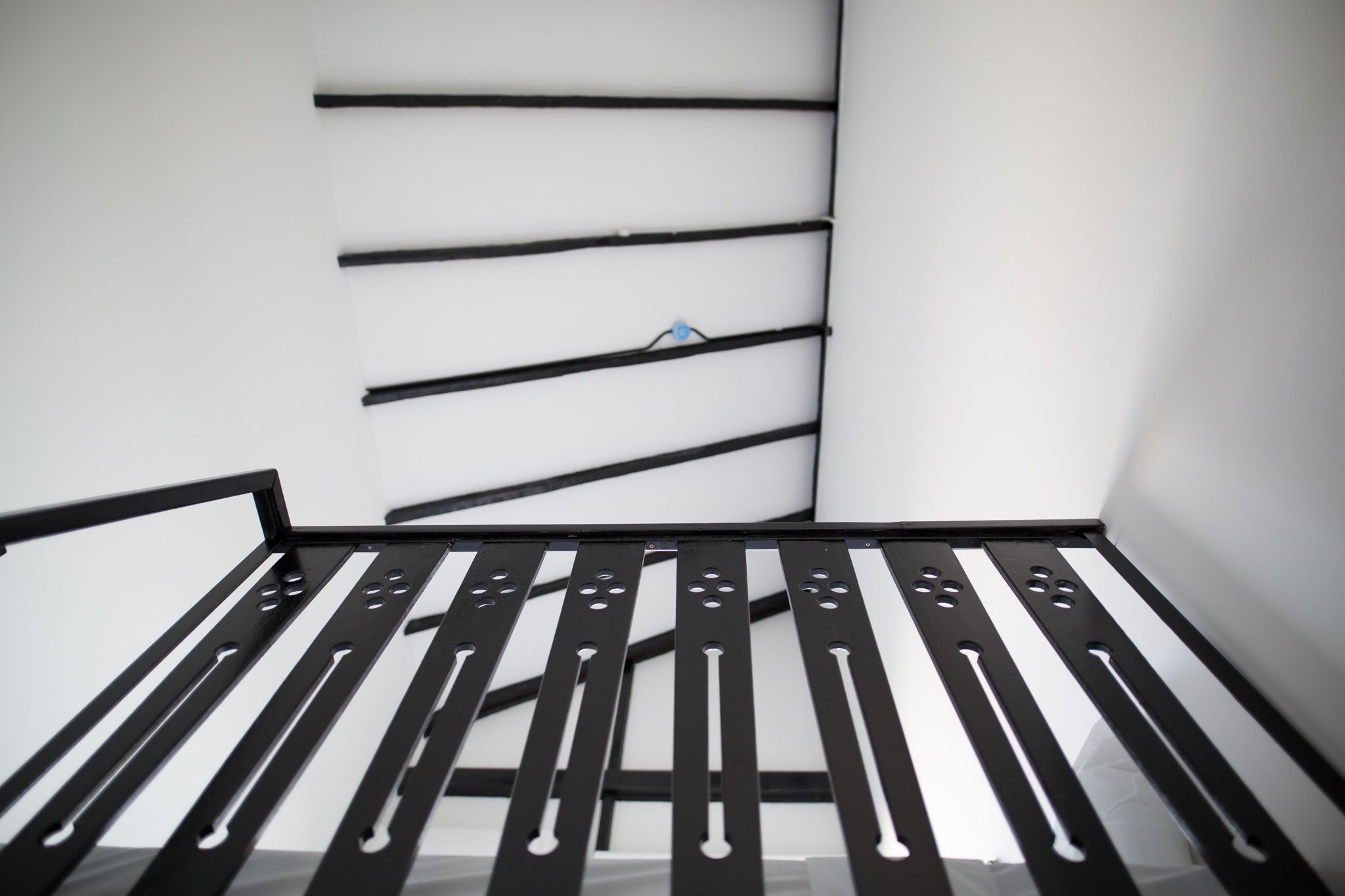 A room with a metal bed frame and a white wall.
