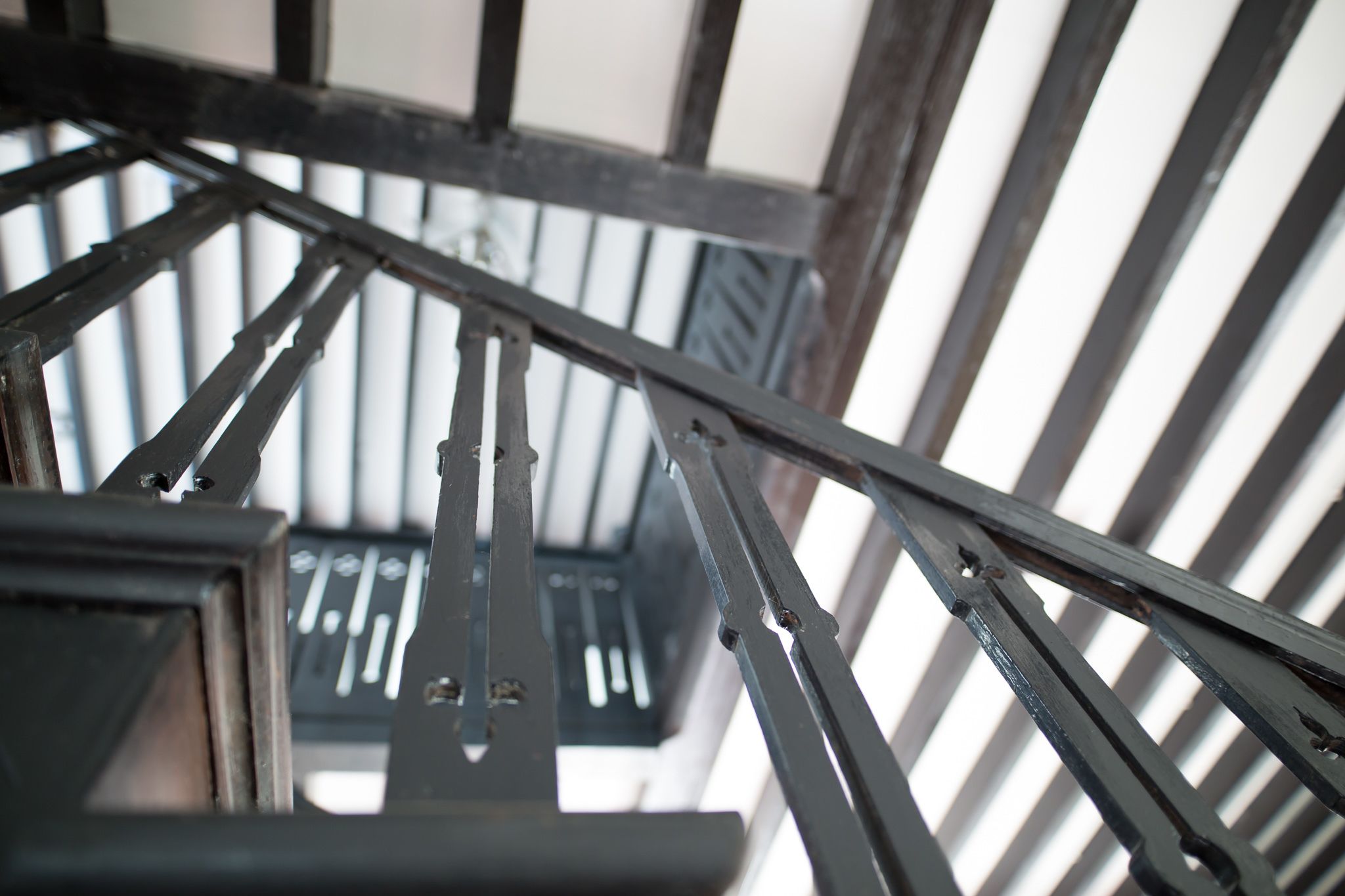 A close-up of a metal staircase railing with a view of the sky through the gaps.