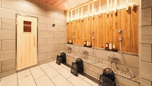 Un baño moderno con paneles de madera, múltiples cabezales de ducha y suelo de baldosas.