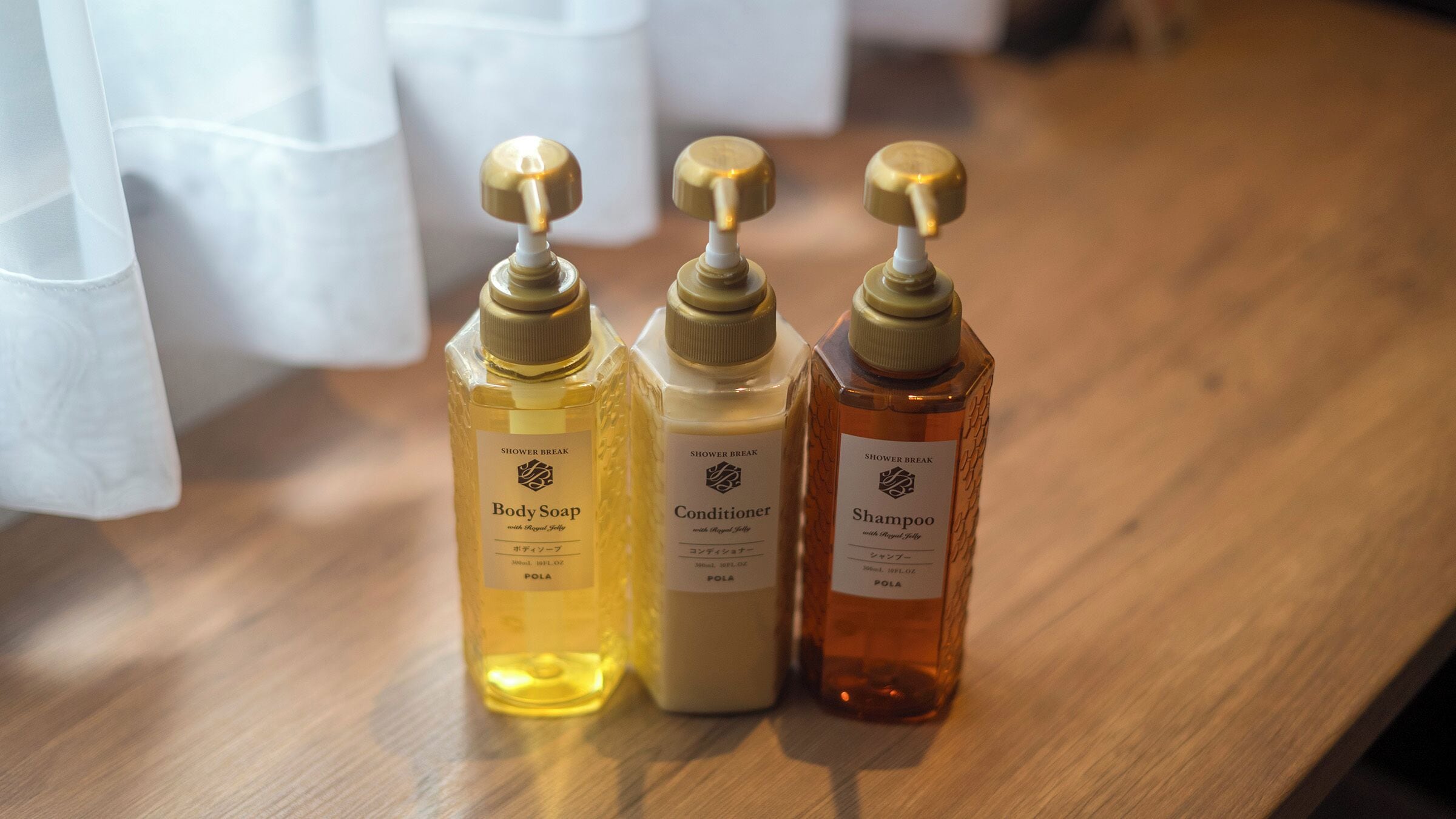 Three bottles of shower break products on a wooden surface.