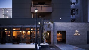 Exterior moderno de un hotel con fachada de vidrio, un letrero que dice 'HOTEL GLOBAL VIEW' y una entrada bien iluminada.