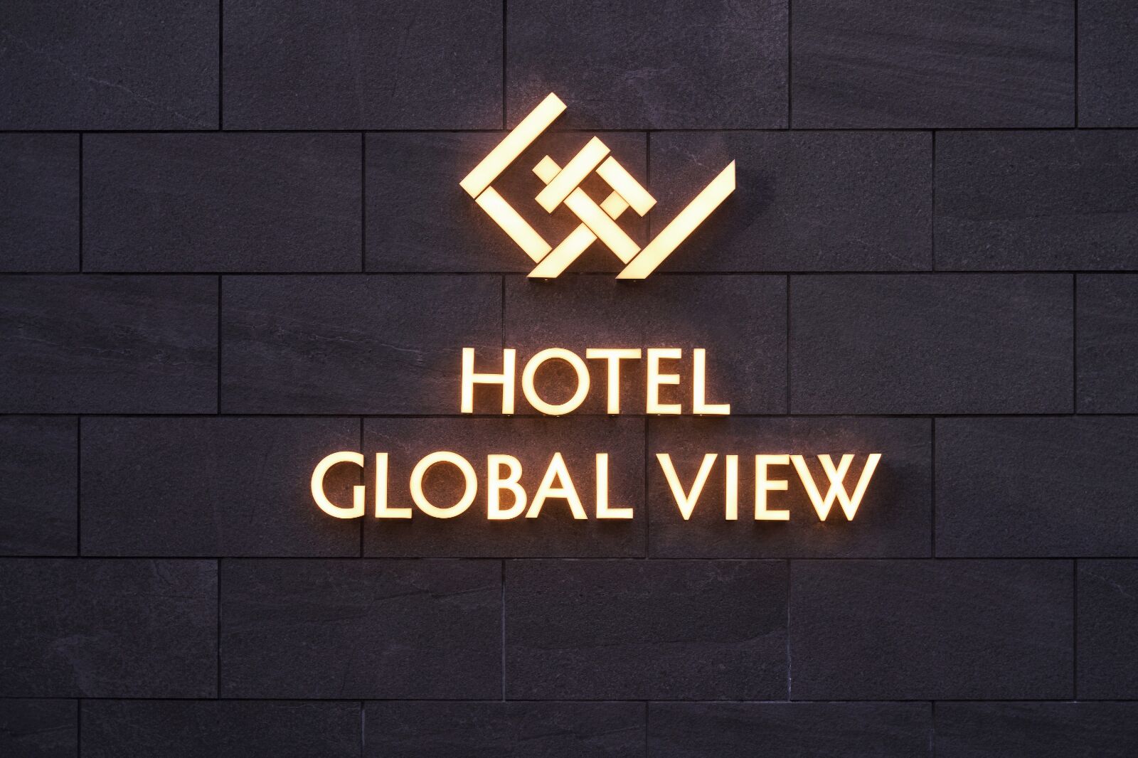 A hotel sign with a geometric logo and the name 'HOTEL GLOBAL VIEW' on a dark tiled wall.