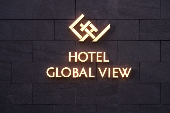 A hotel sign with a geometric logo and the name 'HOTEL GLOBAL VIEW' on a dark tiled wall.