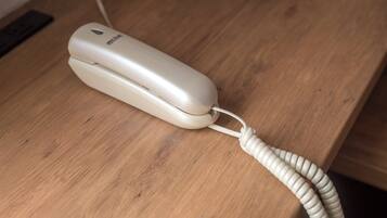 Un teléfono blanco con un cable enrollado sobre una superficie de madera.