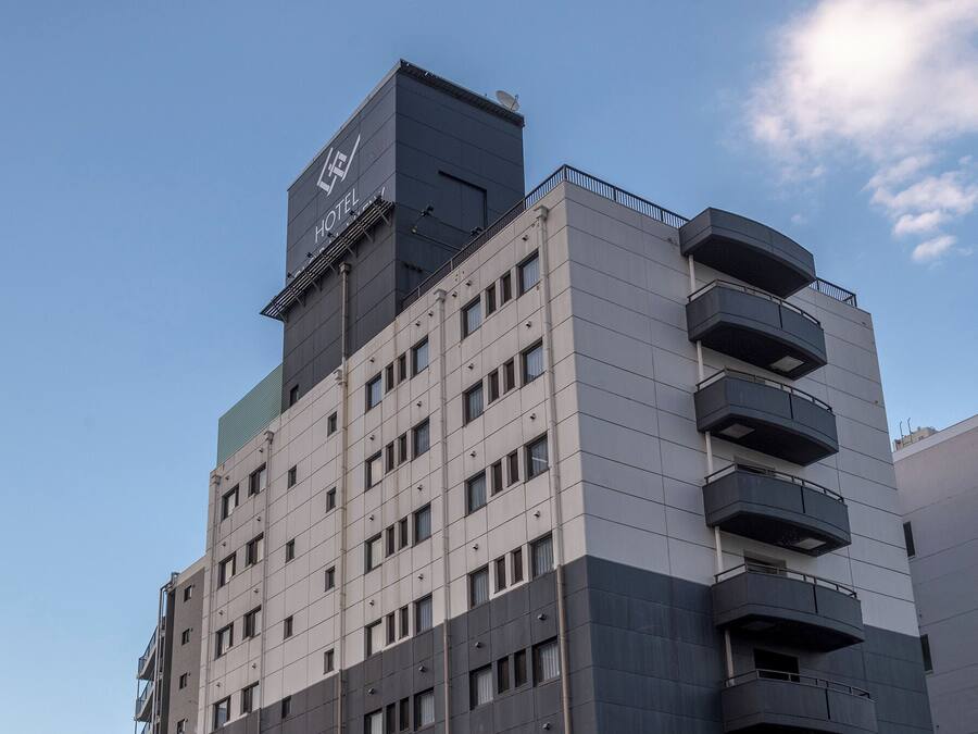 A multi-story hotel with a modern design, featuring balconies on the upper floors and a prominent satellite dish on the top.