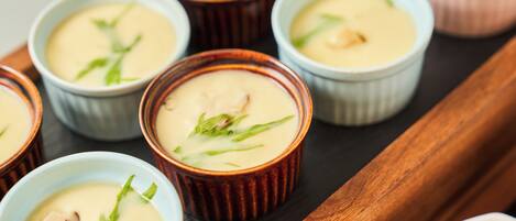 A tray with several small bowls of creamy soup garnished with green leaves.