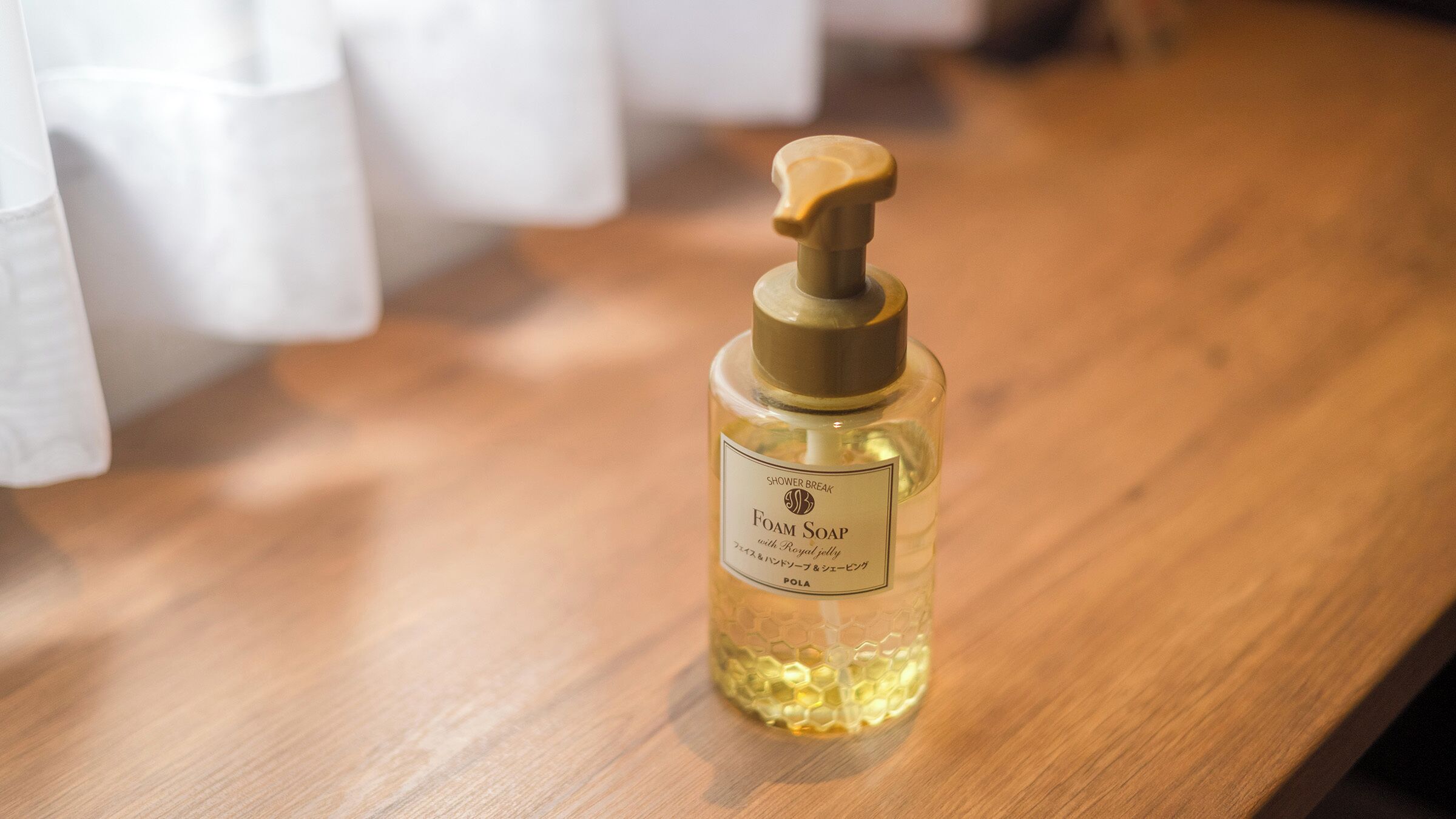 A bottle of foam soap with a pump dispenser on a wooden surface.